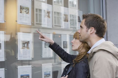 Young couple looking at real estate postings in a window.