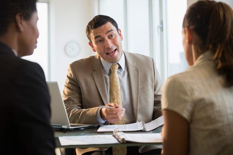 A real estate agent speaks with his clients in an office.