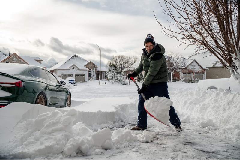 Homeowner shovels sidewalk after snowstorm.