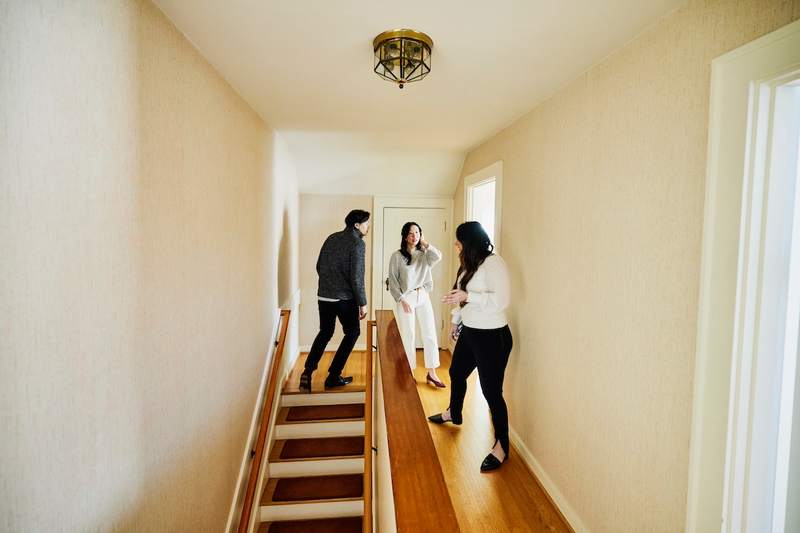 An agent shows a couple the upper floor of an empty home.