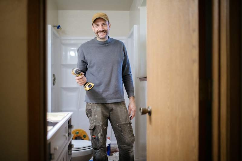 A contractor makes a repair in the bathroom of a house.