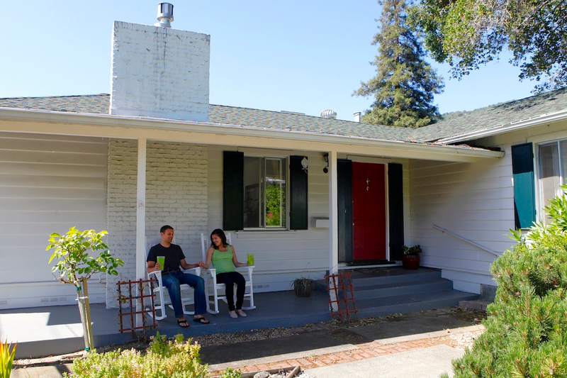 A couple relaxes on the porch of their home.