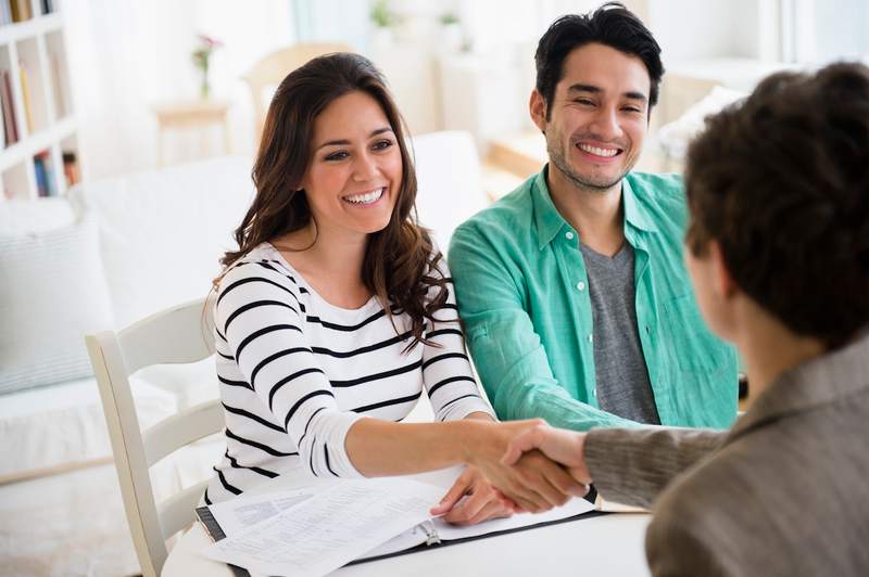 Couple shakes hands with lender after they're cleared to close on their home purchase.