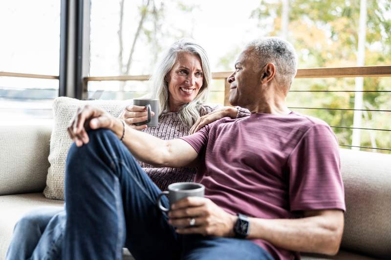 Senior couple relaxes with coffee on the patio.